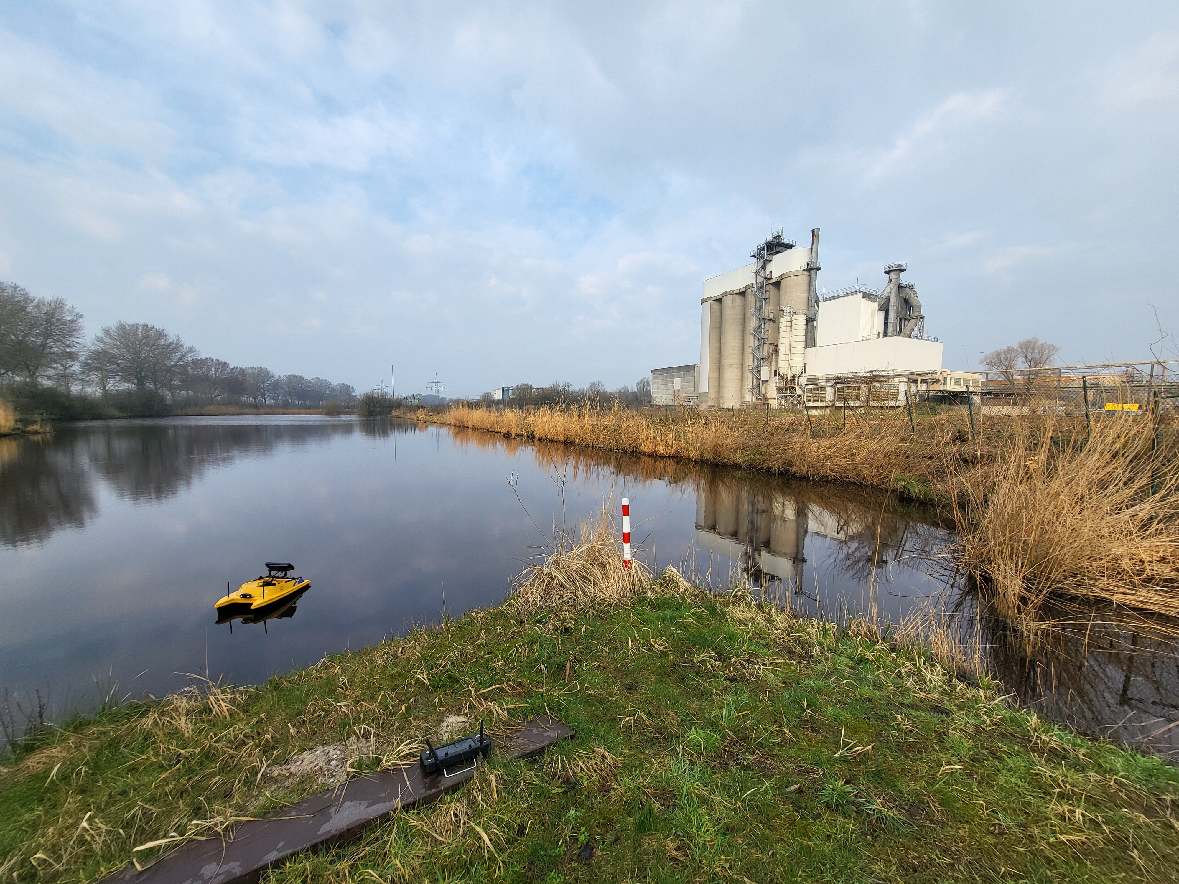 CC Aquascan USV Boot auf einem See vor Industriegebäude